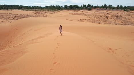 Seguimiento-Aéreo-Hacia-Atrás-De-Una-Mujer-Caminando-Sobre-Las-Dunas-De-Arena-Del-Desierto-En-Mui-Ne-Vietnam