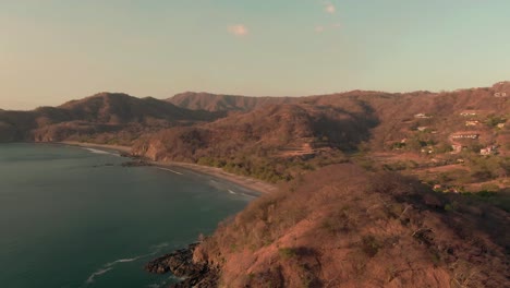 aerial flight above rock beach coastline in warm costa rican sunset