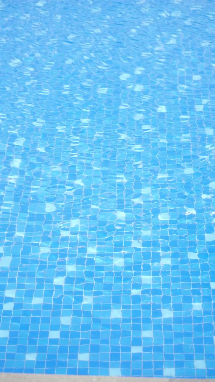 Klares blaues Wasser, das sich in einem gefliesten Schwimmbecken kräuselt