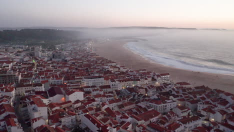 Vista-Aérea-De-La-Riviera-De-La-Playa-De-Nazare-Con-El-Paisaje-Urbano-De-La-Ciudad-De-Nazare-En-Portugal---Toma-Aérea-De-Drones