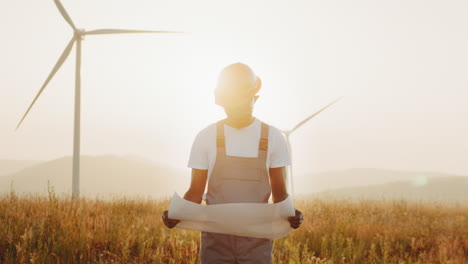 engineer reviewing plans for a wind farm at sunset