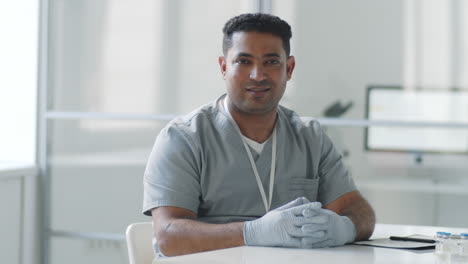 positive middle eastern male doctor posing for camera at work