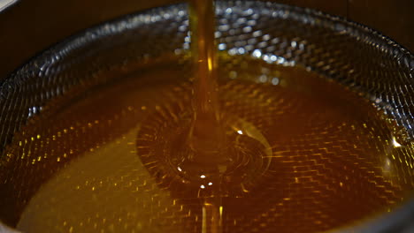 beautiful liquid freshly extracted honey flowing on the sieve. close up. organic product gathered at the apiary.