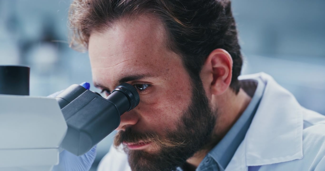 Scienziato guarda al microscopio in laboratorio