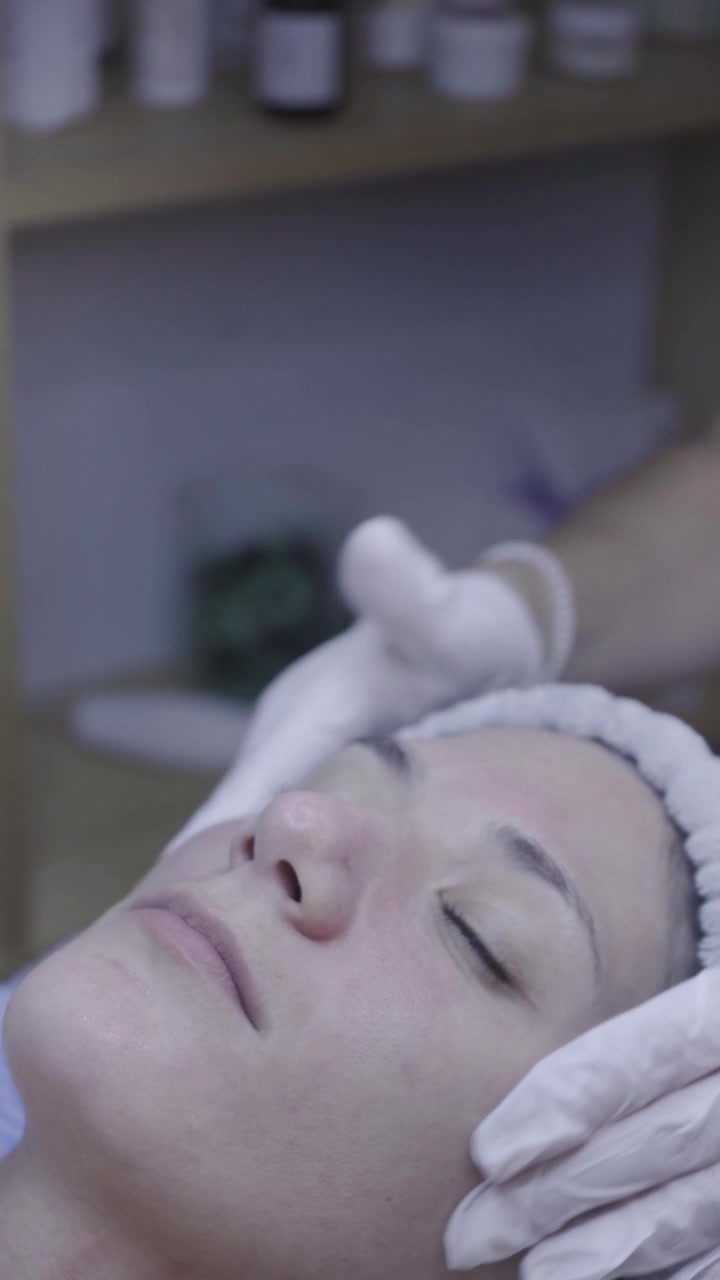 Mani guantate accarezzano il viso durante un rilassante rituale viso in spa