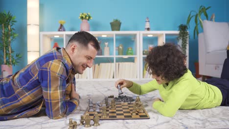 The-boy-is-preparing-to-eat-his-father-in-chess,-they-are-having-fun-with-each-other.