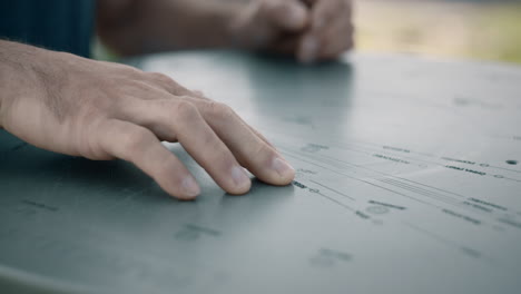 Closeup-shot-of-man-hiker-hands-and-finger-touching-on-the-metal-mountain-map-on-the-top-of-the-hill-Kum-in-Slovenia