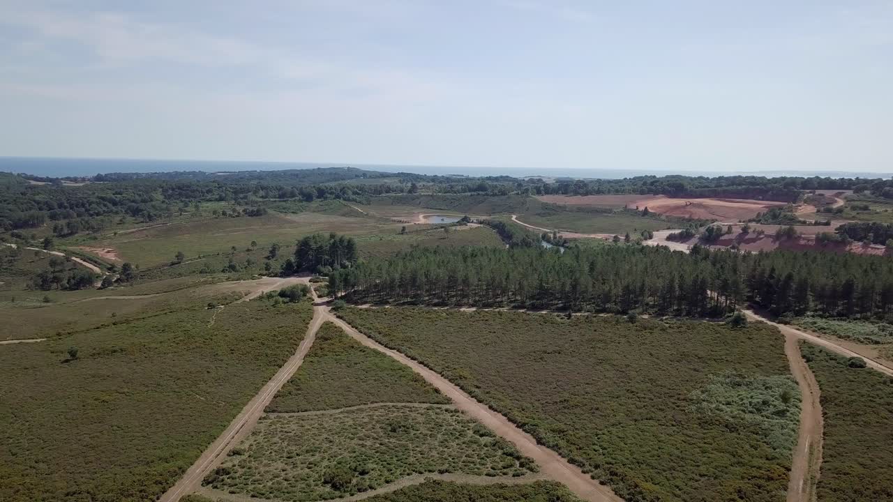 Aerial view of a natural landscape with sea, trees, and paths