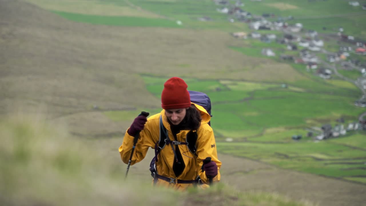 un excursionista escalando una montaña cubierta de hierba en villingadalsfjall, islas feroe, concentrado y tranquilo
