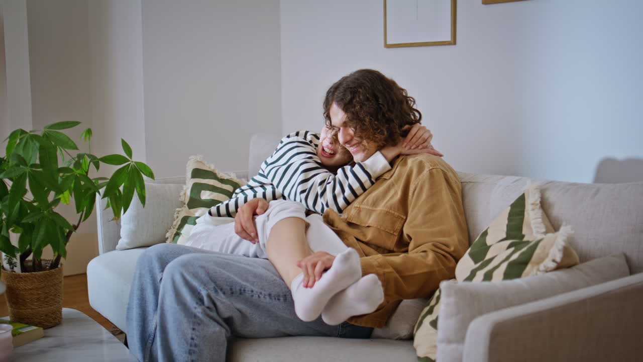 Happy spouses cuddling couch feeling tenderness. Smiling woman hugging man sofa