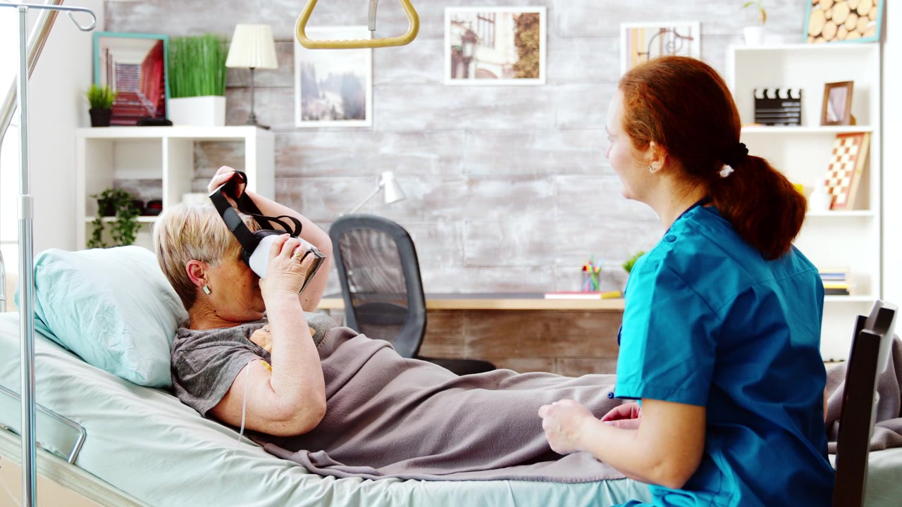 Sygeplejerske hjælper ældre patient med virtual reality-headset på hospitalsstue