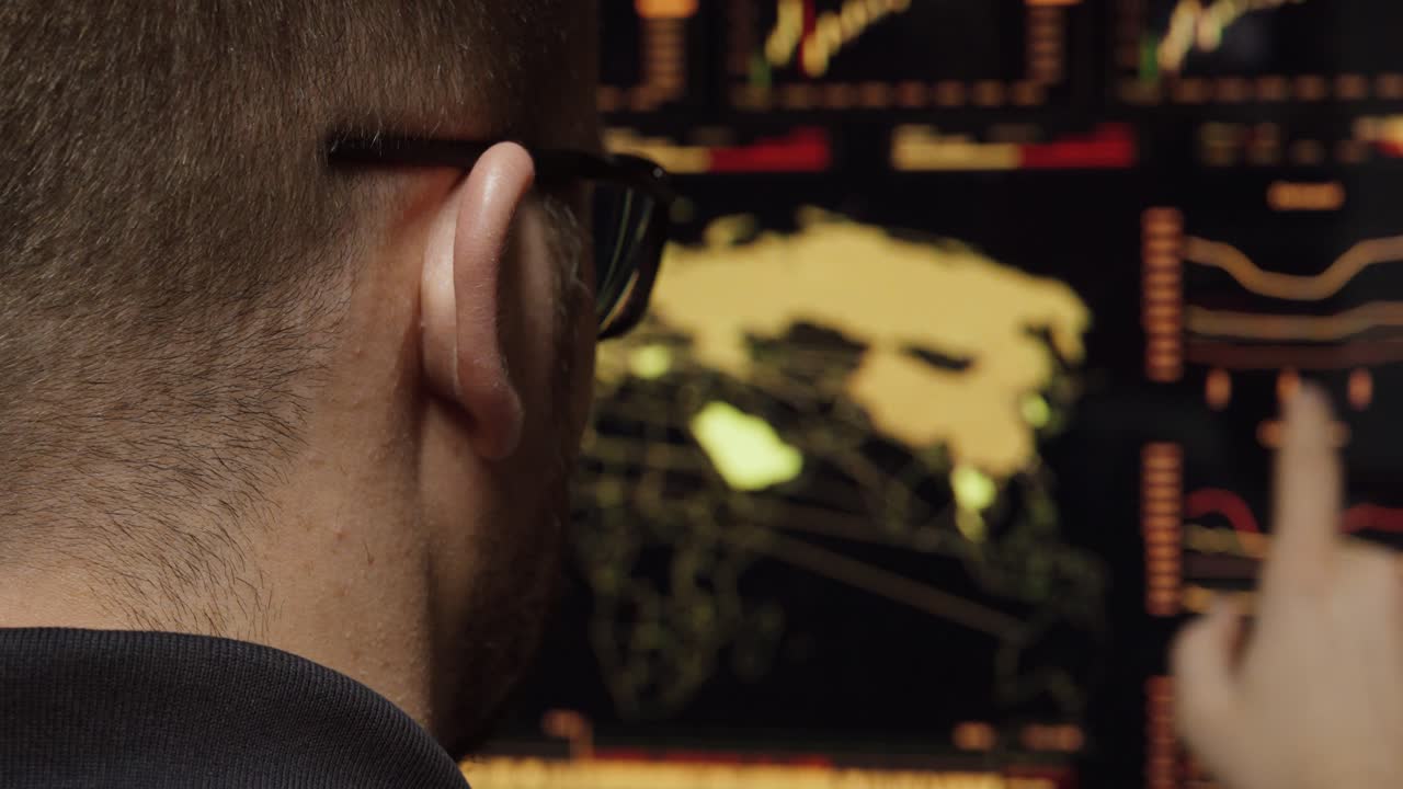 Rear view of a man analyzing a digital world map and data charts on multiple screens, illustrating cybersecurity monitoring, global network surveillance and real-time data analysis