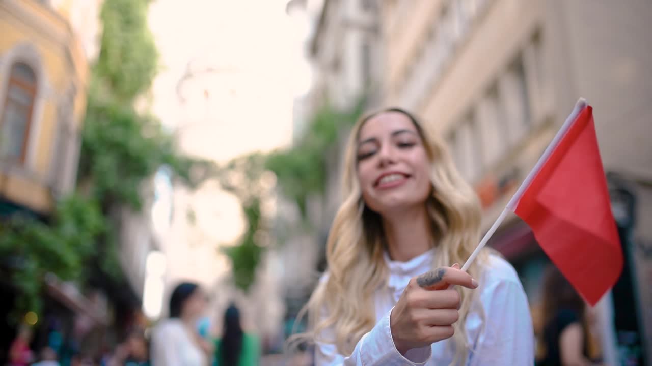 cámara lenta: atractiva joven hermosa ondea la bandera turca frente a la torre de gálata, un punto de referencia popular en estambul, turquía