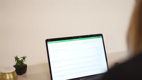 Woman-typing-on-laptop-in-office,-rack-focus-from-shoulder-to-computer-screen