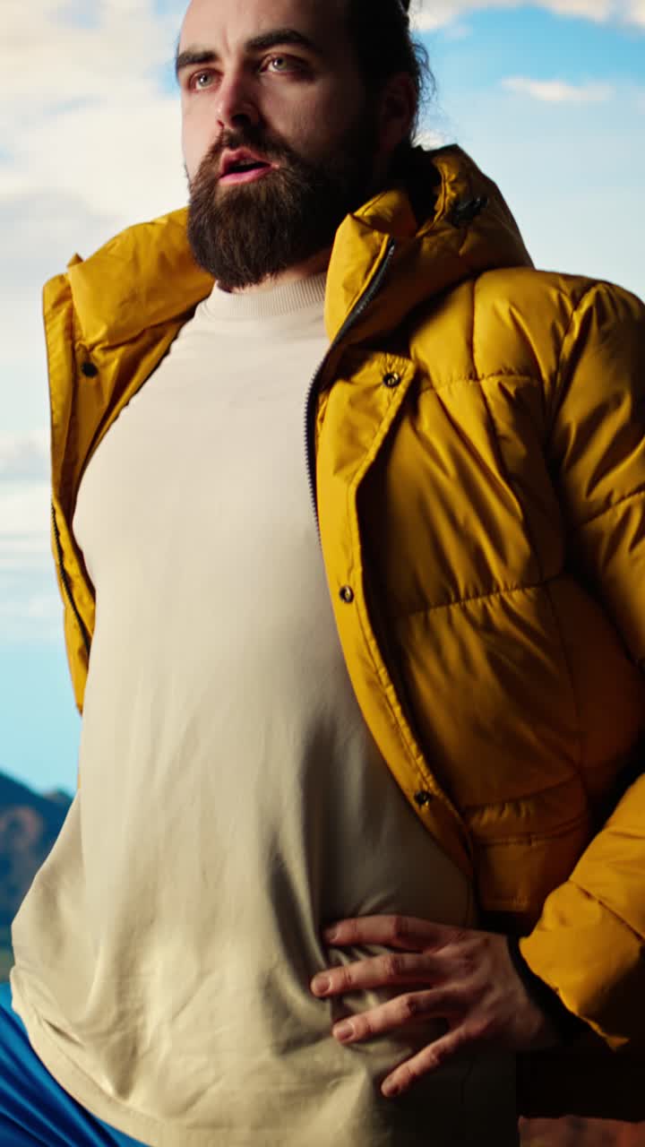 Uomo in piumino giallo in piedi sulla cima di una montagna