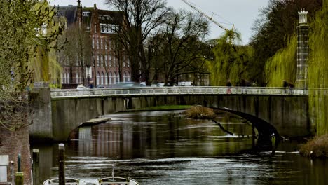 Beautiful-Time-lapse-of-people-and-cars-crossing-bridge-over-river-in-Den-Bosch,-the-Netherlands---zoom-out