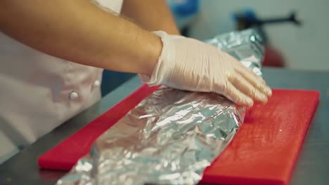el cocinero envuelve la carne en escabeche en papel de aluminio para la posterior