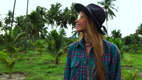 Happy-redhead-woman-with-sunglasses-and-hat-in-tropical-jungle,-front-view