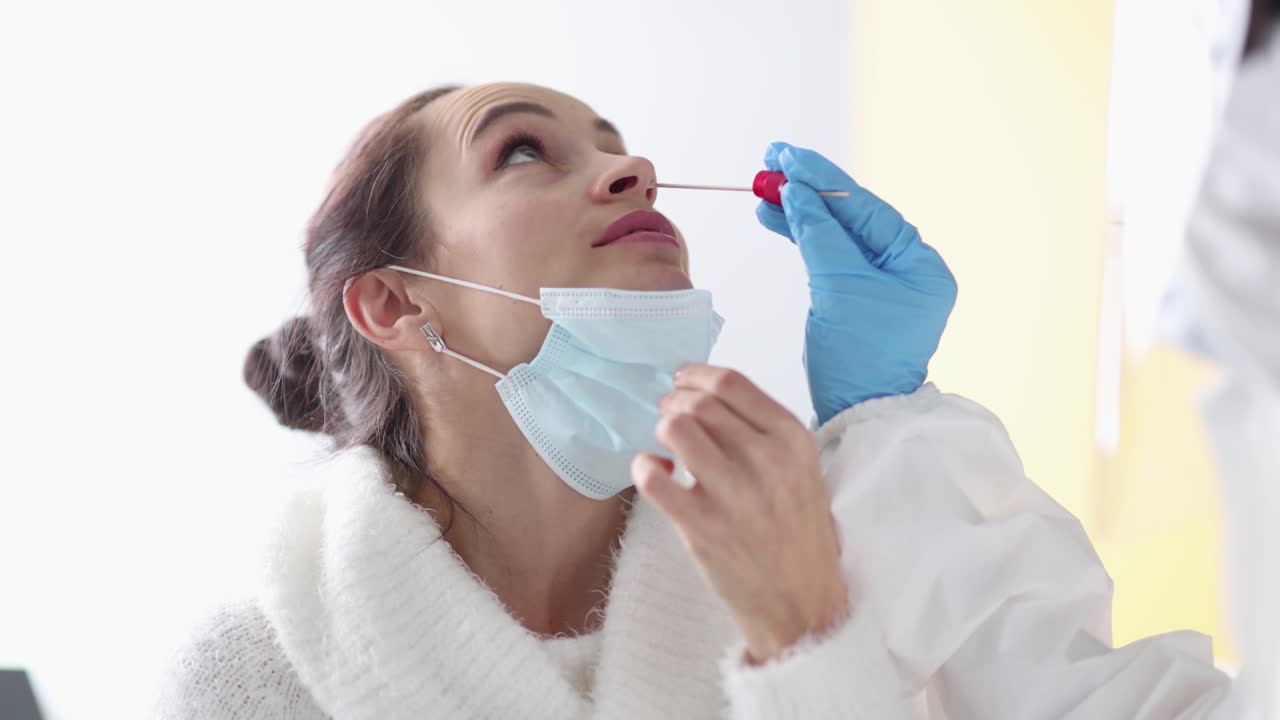 Médico tomando muestra de la nariz del paciente para diagnóstico PCR de COVID-19, película 4K en cámara lenta.