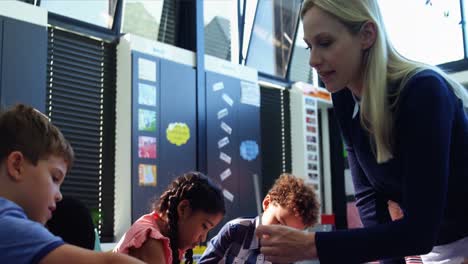 teacher helping schoolkids with their homework in classroom
