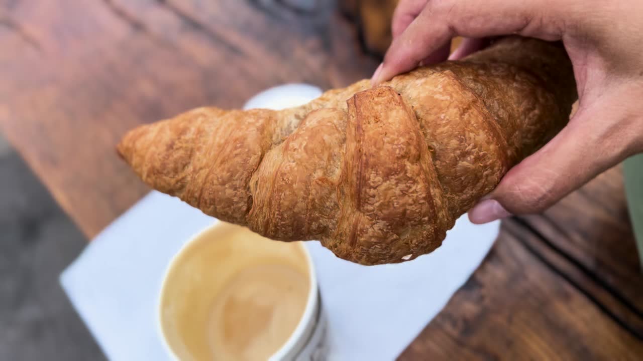 Dipping Croissant Into a Cup of Frothy Latte