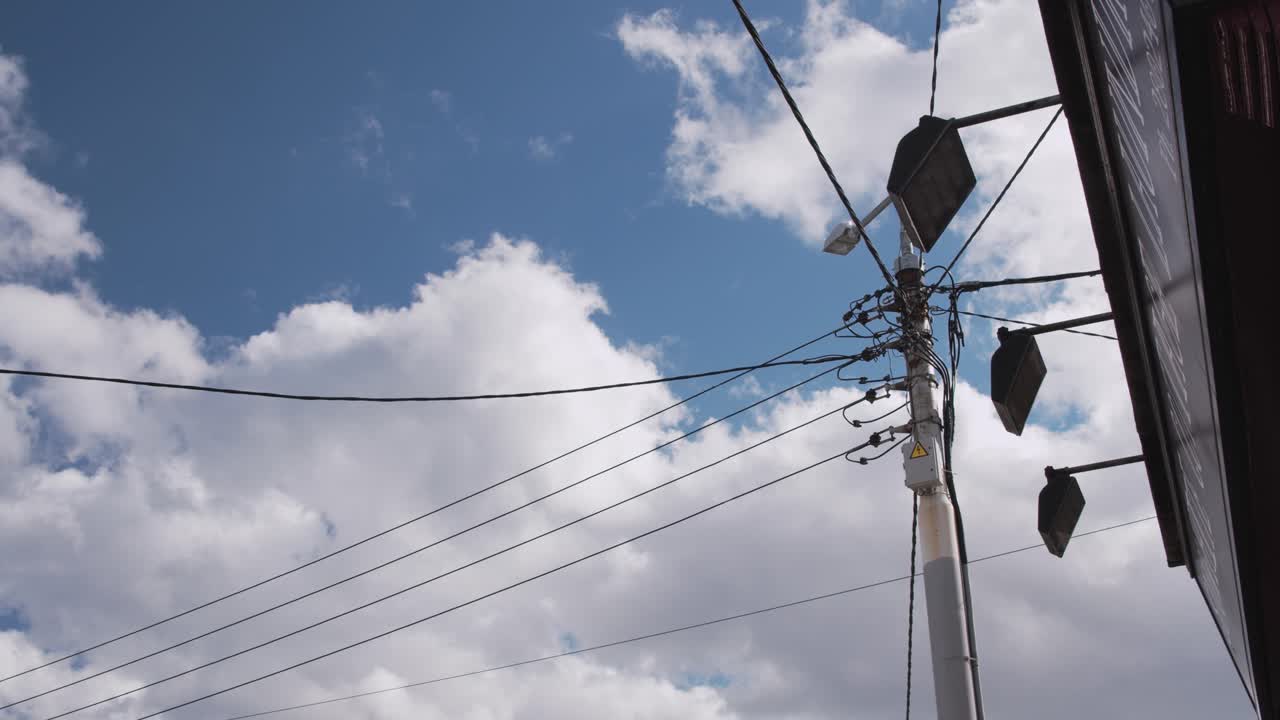 Overhead Power Lines and Street Lights Against a Cloudy Sky