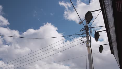 overhead power lines and street lights against a cloudy sky