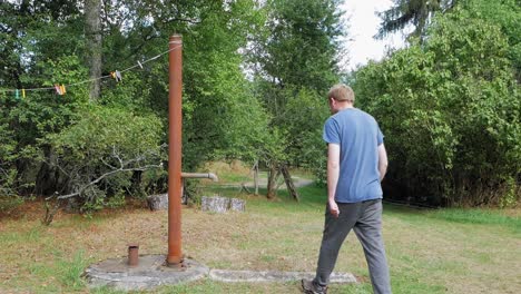 caucasian man manually pumps water from a well in prądzonka poland - medium shot