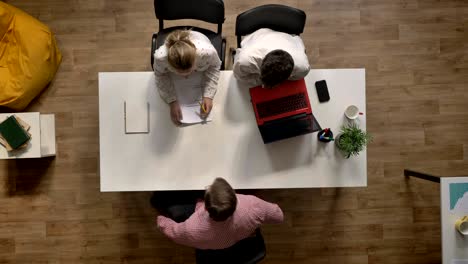 un candidato masculino para un trabajo es entrevistado por dos empleadores, topshot, sentado en una oficina moderna
