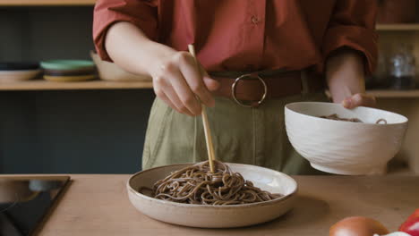 woman cooking and serving delicious buckwheat noodles