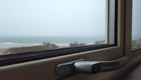 close up of rain flowing down a window with the ocean visible in the background