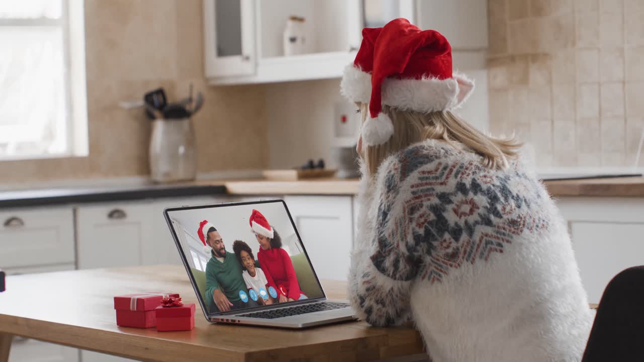 mujer caucásica teniendo una videollamada de navidad con su familia