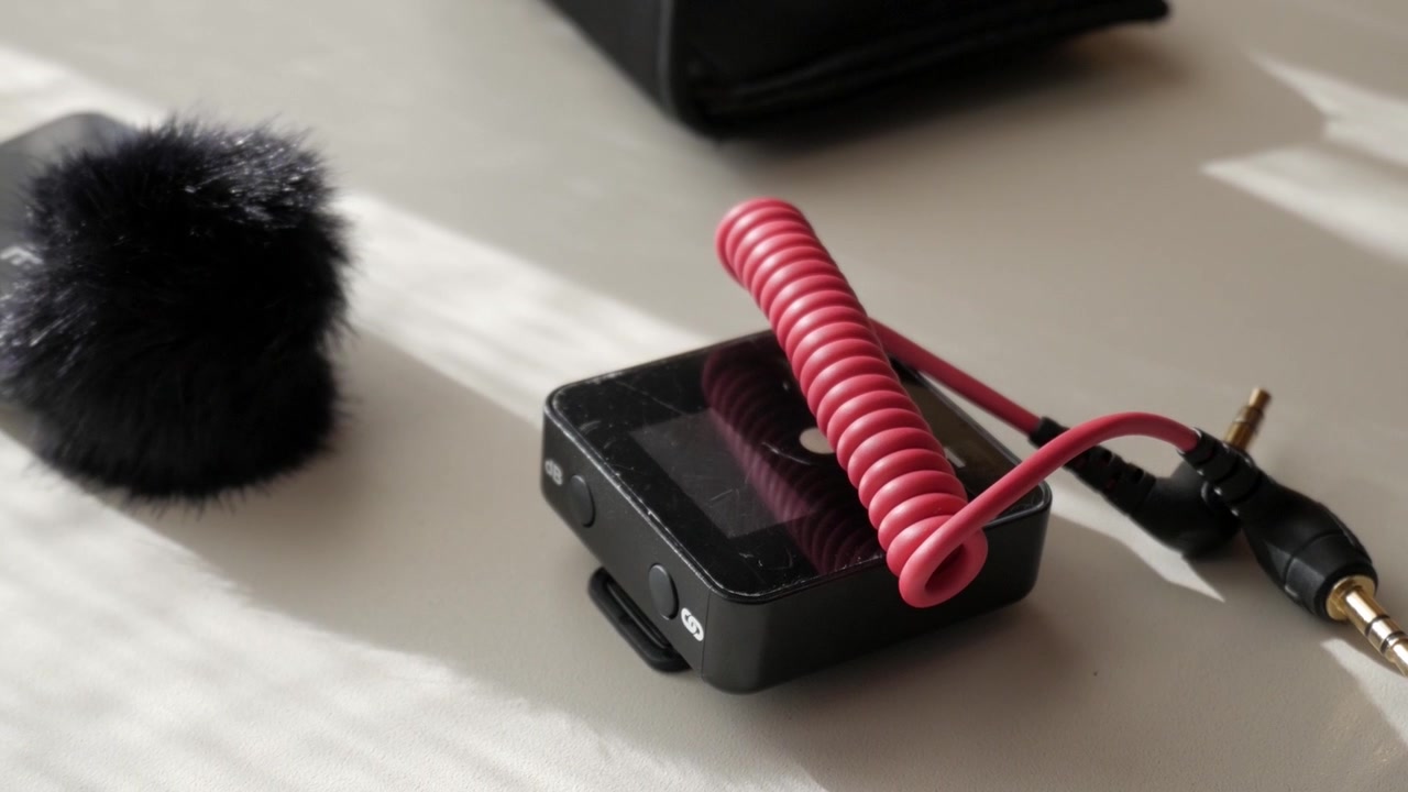 Micrófono de solapa compacto y conjunto de adaptador sobre una mesa con luz natural.