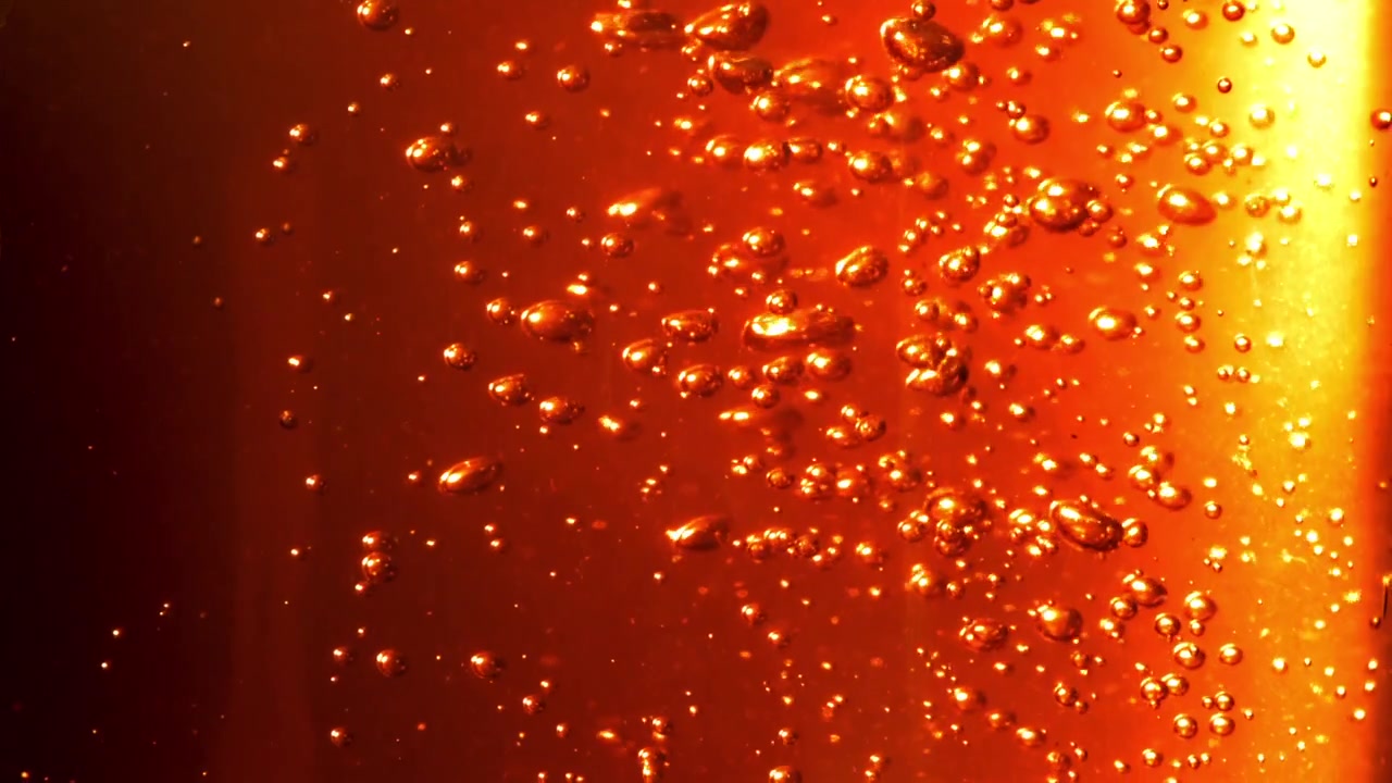 Bolle dorate che salgono in un liquido arancione frizzante