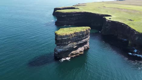 drone shot flying away from downpatrick head with mainland in the background