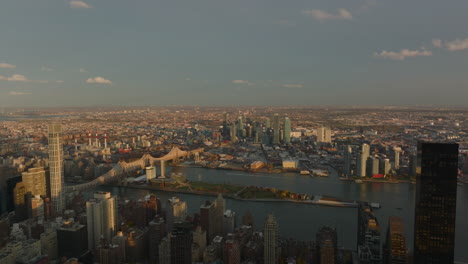 Aerial-descending-footage-of-Queensboro-Bridge-and-buildings-in-Queens-borough-in-sunset-time.-Manhattan,-New-York-City,-USA