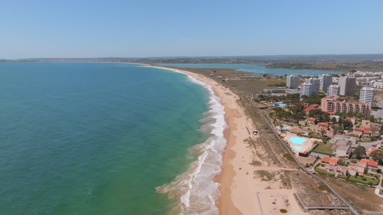 Drone em movimento de dolly sobre praia de areia dourada na Praia dos Três Irmãos, Algarve, Portugal.