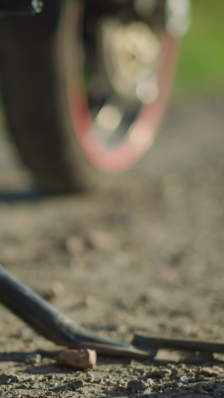 Close-up of a biker removing the kickstand of the motorcycle, as she drops one leg for, the front tire is slightly turned to the left, while the background and foreground are blurred