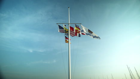 Several-flags-for-Canadian-provinces,-the-United-States-and-other-countries-flap-in-the-wind-on-a-single-flagpole