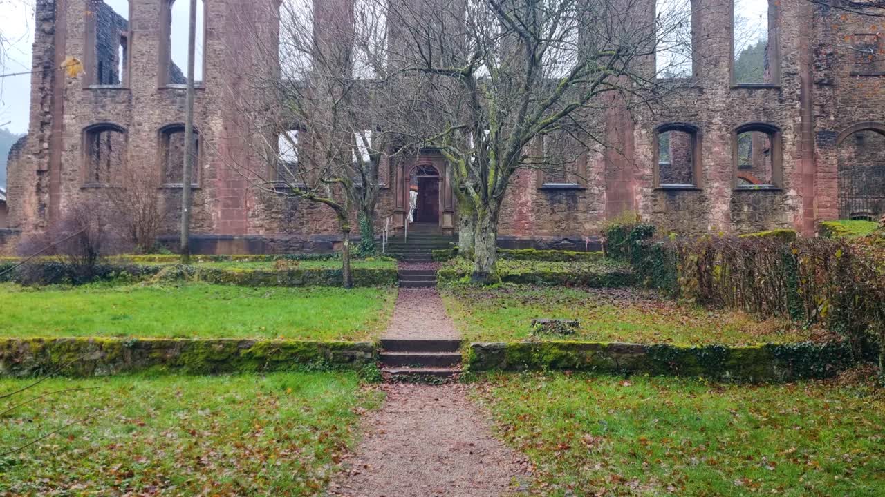 Zijaanzicht van de ruïnes van het Frauenalb-klooster in Bad Herrenalb, Duitsland, vastgelegd op een natte, bewolkte herfstdag, met geërodeerde stenen muren en klokkentorens die een sombere, sfeervolle stemming creëren