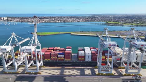 large cargo ship docked beside cranes at melbourne container port in port phillip bay