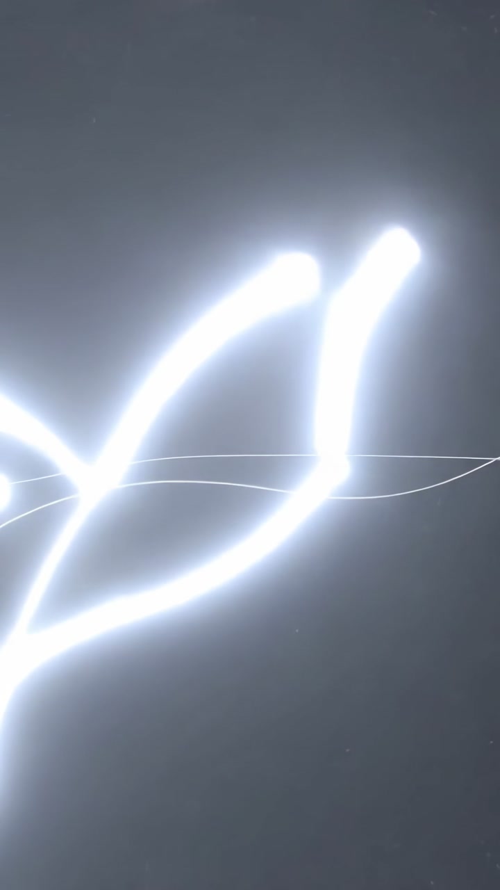 Vertical video: Wavering bright band sending curving light arcs in dark void, with thin line