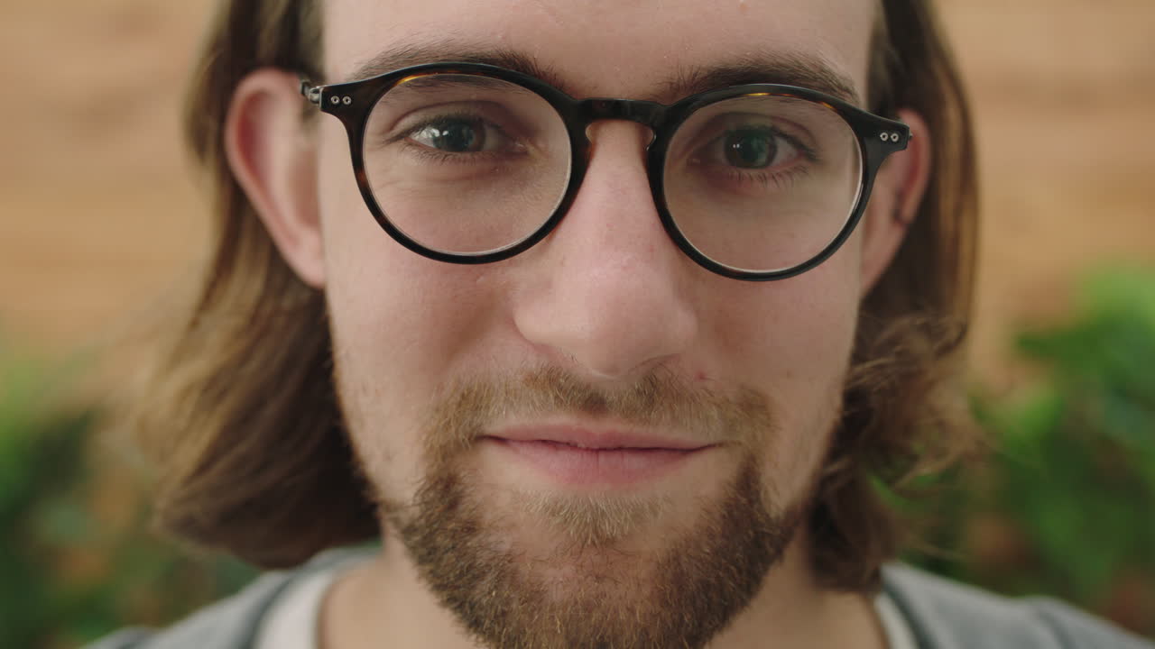 retrato de um jovem geek confiante olhando pensativo para a câmera usando óculos