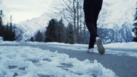 person walking down a snowy road closeup shot slow motion