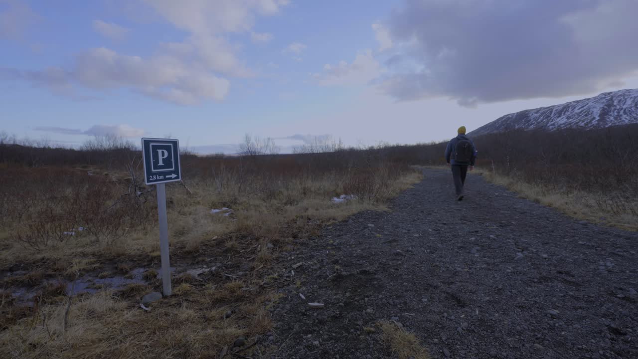 아름다운 날씨와 눈 덮인 산을 배경으로 돌길을 따라 걷는 배낭을 메고 있는 남자