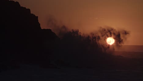 Massive-waves-break-against-a-rocky-shore-at-sunset-in-slow-motion