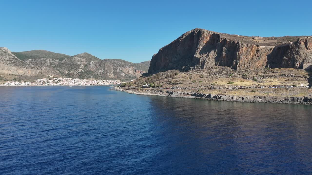 Peloponnes, Monemvasia, Luftaufnahme aus der Vogelperspektive, die von der Neustadt nach rechts in Richtung der alten Zitadelle gleitet und das wunderschöne Panorama an einem sonnigen, ruhigen Tag mit blauem Himmel und Meer abdeckt