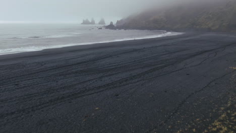 aerial pan up at vik iceland early winter fog at black sand beach waves crashing on shore