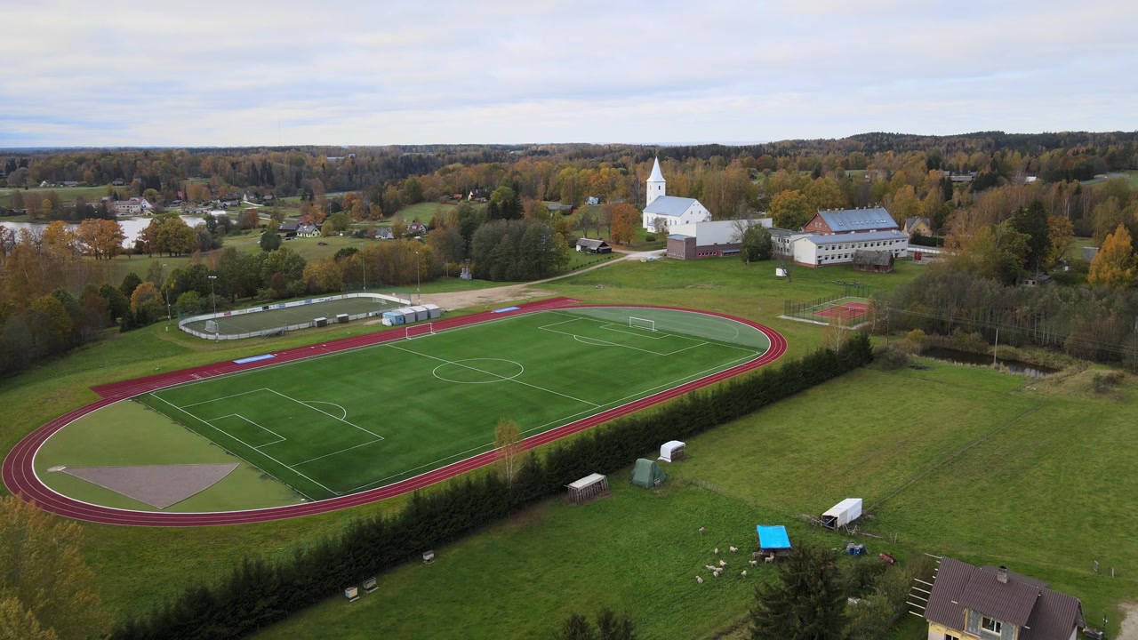 4K Drone Footage of Green Stadium Surrounded by Autumn Forest in Estonia