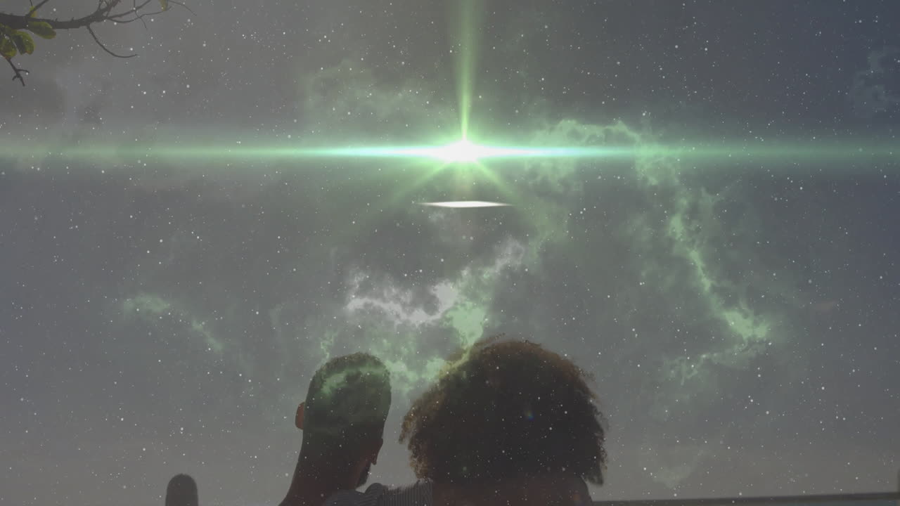 Observing green aurora and stars, silhouetted people standing together at night